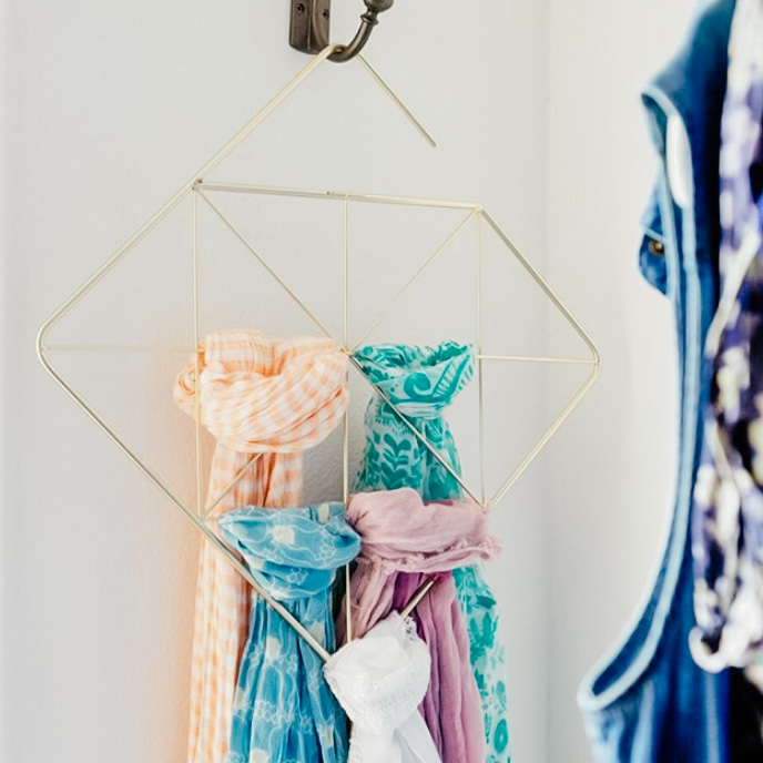 Image Description: Four multi-colored  scarves hang on a diamond-shaped scarf organizer