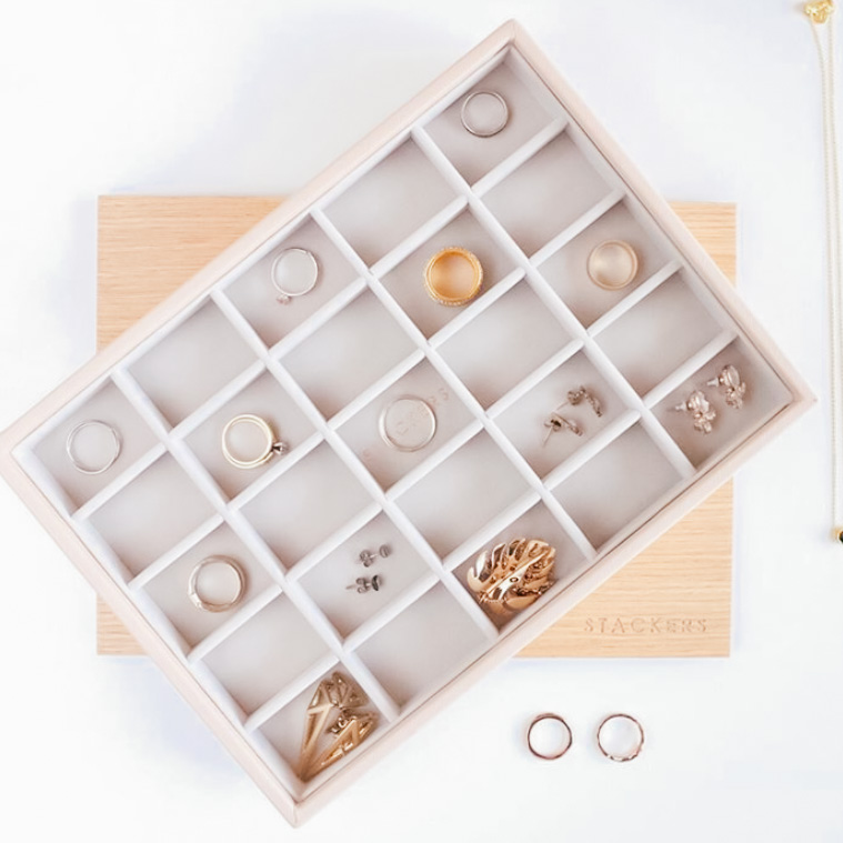 Image Description: A brightly lit jewelry box with inserts is filled with rings and necklaces