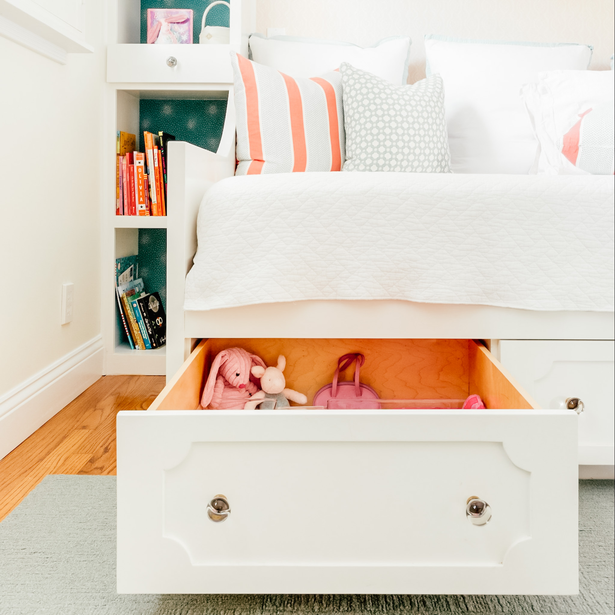 A day bed with a pull-out drawer open below it, filled with stuffed animals