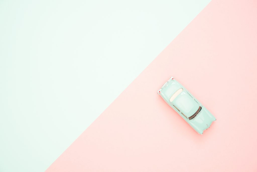 Image Description: A pale, mint green toy car sits on a pink and green background