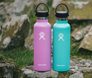 Image Description: Two Hydroflask water bottles in pink and blue sit on a rock.