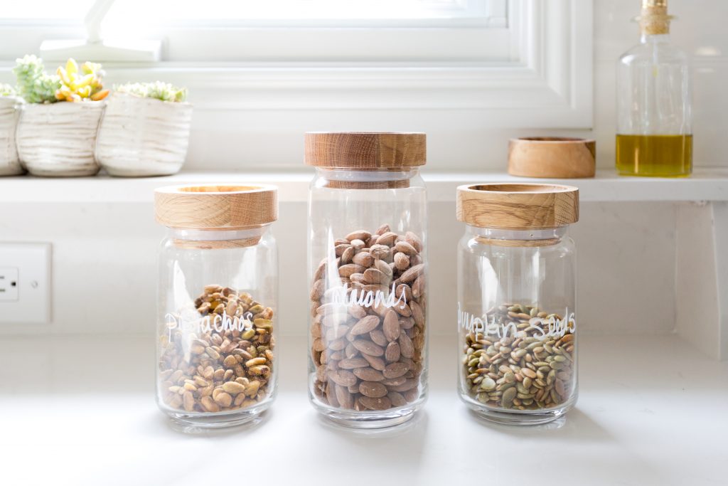 Image Description: Three glass jars with a wooden lid sit on a white countertop.