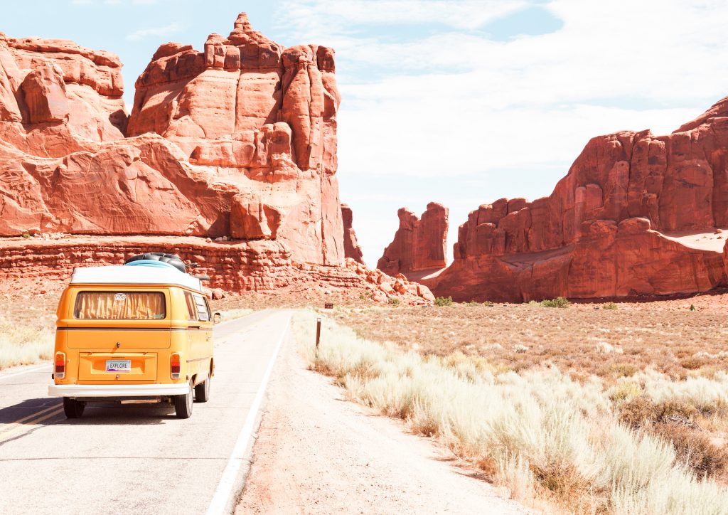 Image Description: A yellow camper can drives toward a red rock formation in the desert