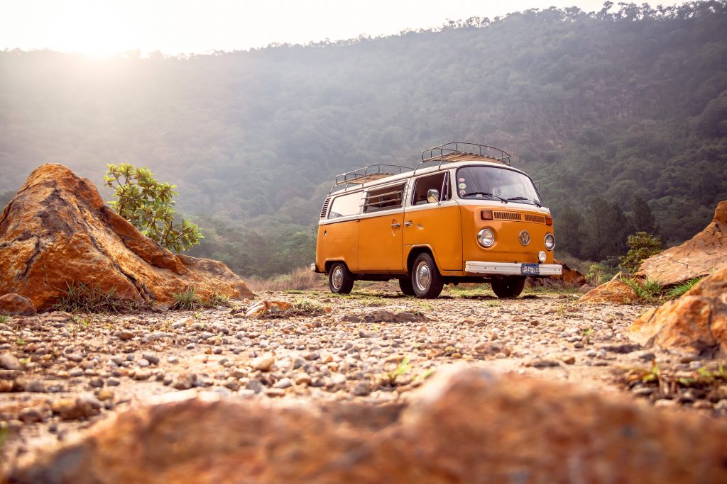 Image Description: A yellow camper can is parked in the middle of a rocky forest