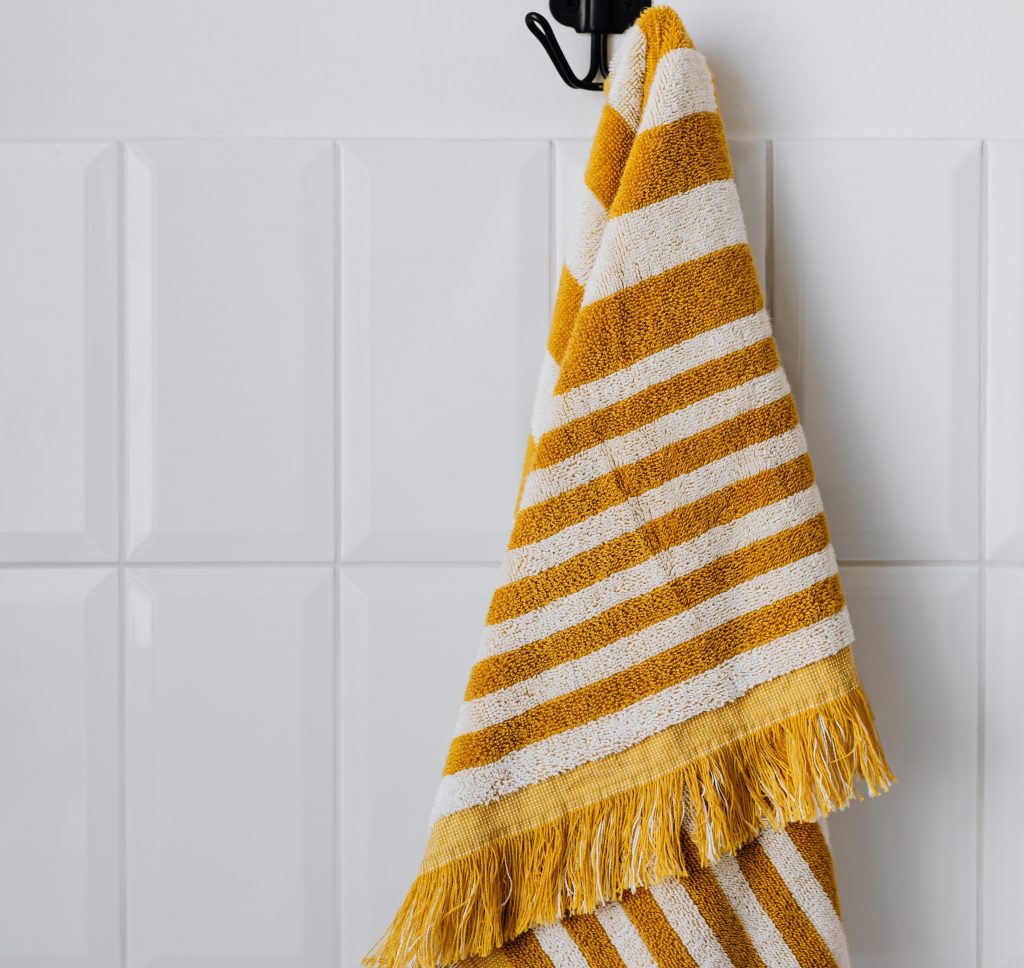 Image Description: A white and yellow striped towel hangs against white tile