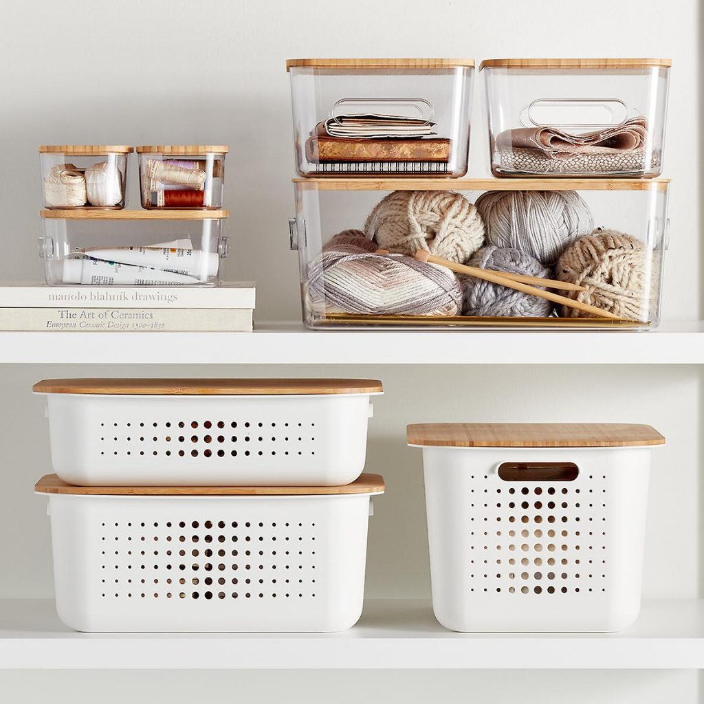 Image Description: Stacked white bins sit below clear acrylic bins with knitting materials, on a shelf.