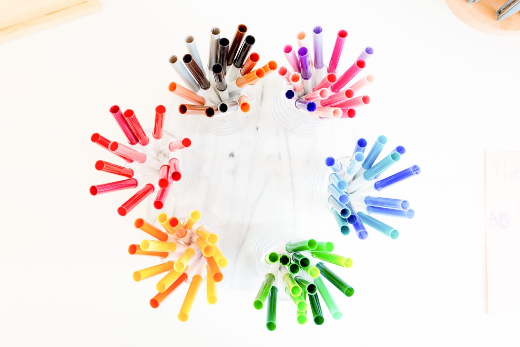 Image Description: Colored markers in glass jars sit on a round marble turntable
